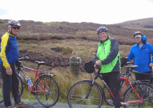 Cyclists chat with man workng in Irish Bog