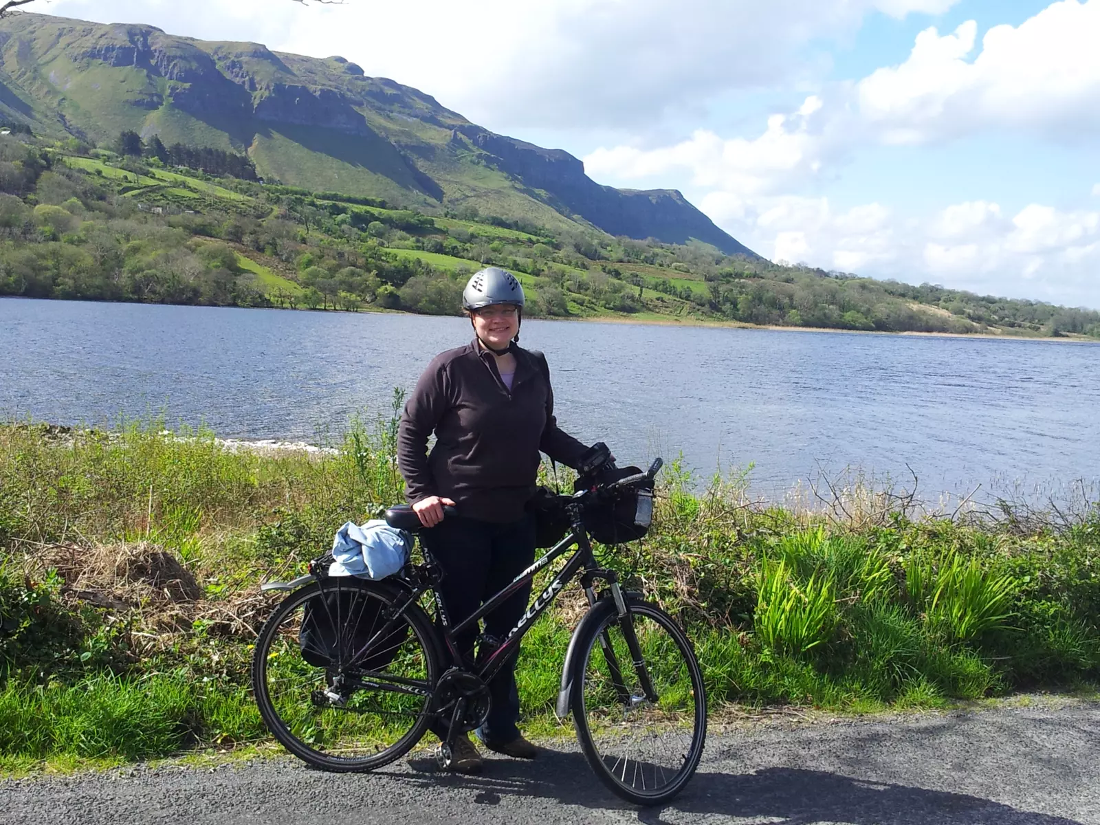 Girl with bicycle standing beside a lake.