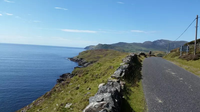Cyclist on quiet road overlooking the sea.