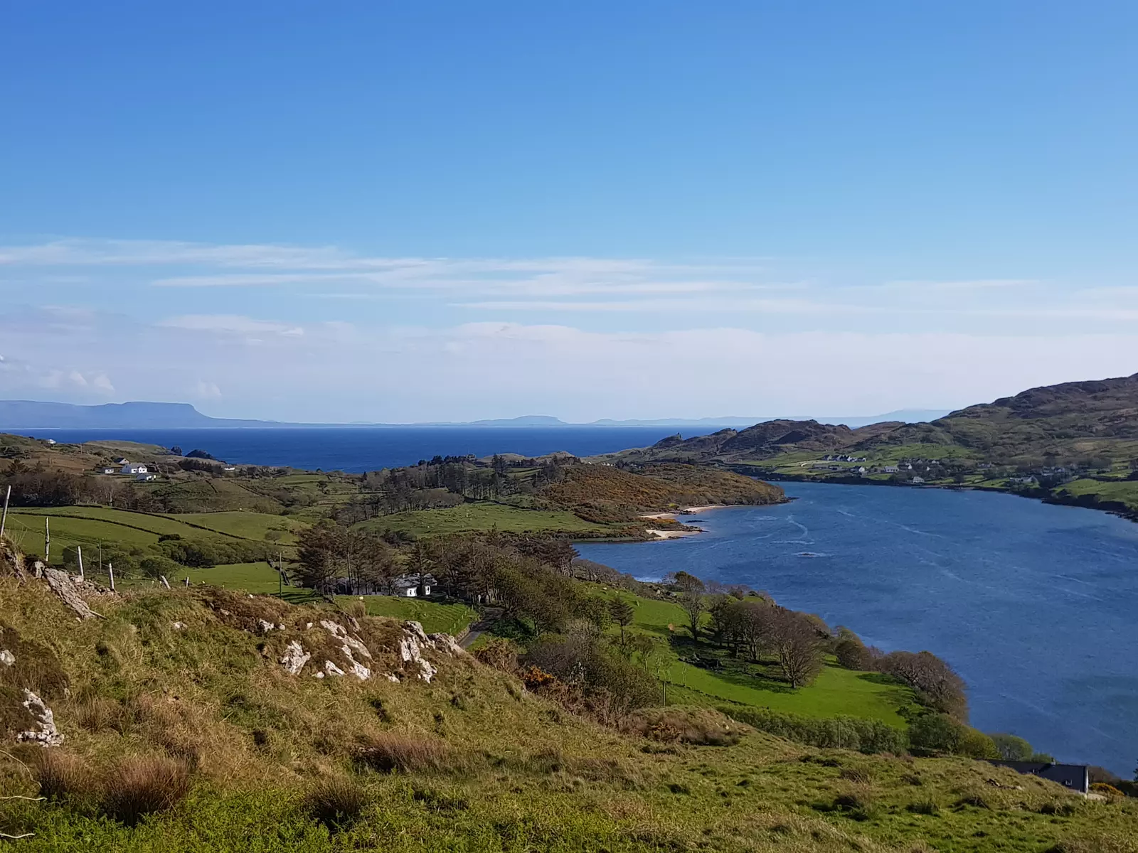 View of a bay surrounded by green fields and hills