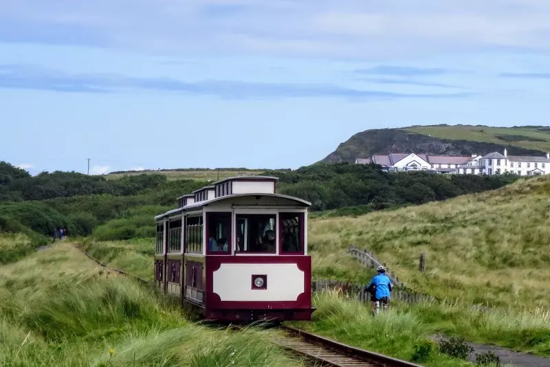 Vintage train with cyclist cycling on a path along the tracks
