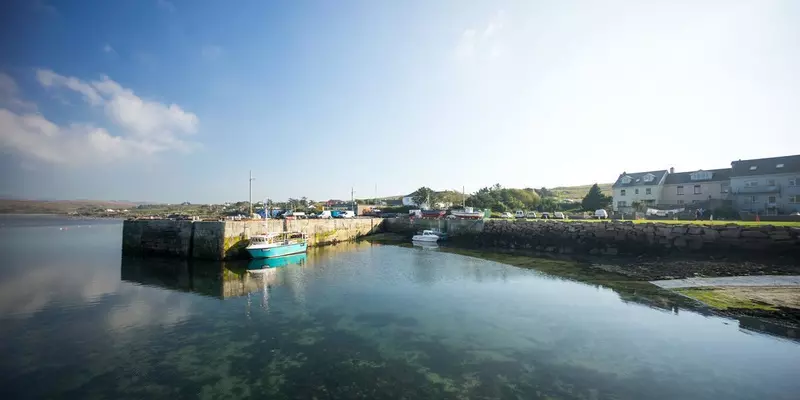 Small pier with boat. Houses along pier.