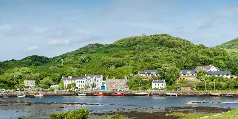 Harbour with small boats with houses and green hills.