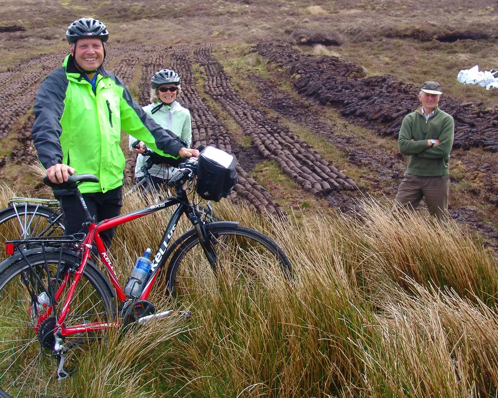 Cyclists along with man harvesting peat.