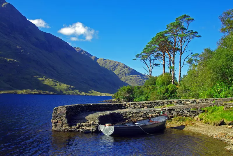 Boat at a small pier with blue sky and mountains