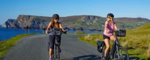 Two girls cycling e-bikes near the coast