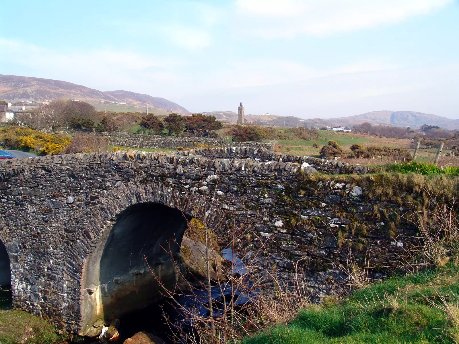 Stone bridge with church spire in distance.