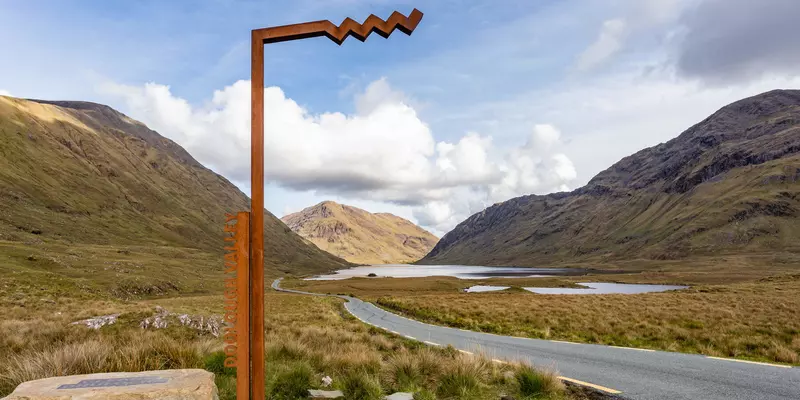 Iron marking post set in remote valley with lakes and mountains.