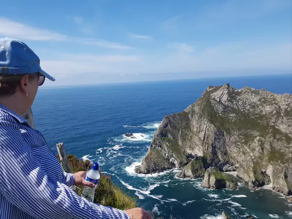 Woman wearing blue looking at rocky shoreline