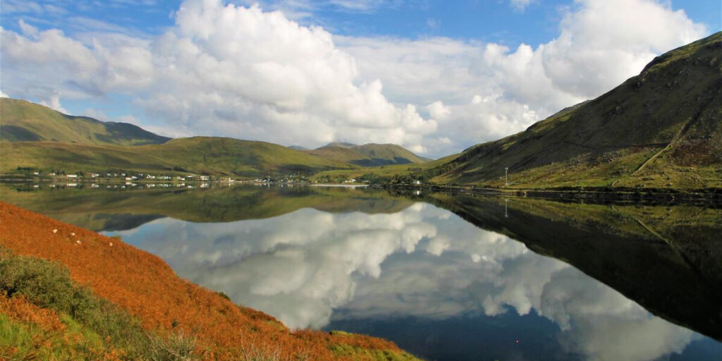 Water with reflection of sky surrounded by hills.