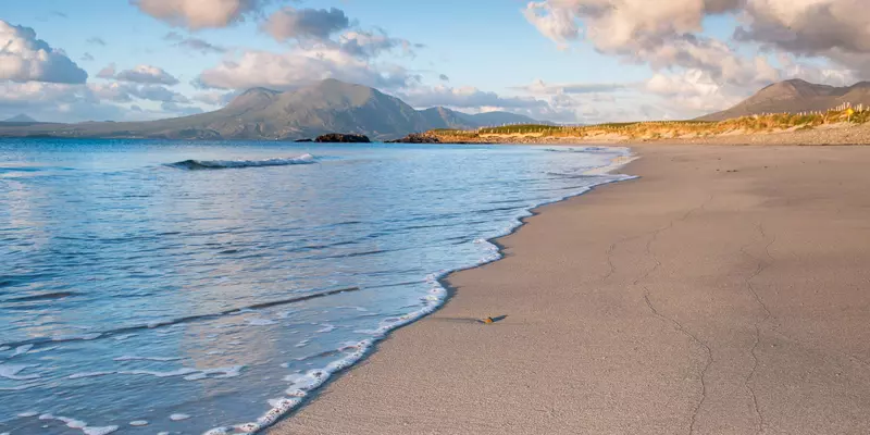 Sandy beach with mountains in the background.