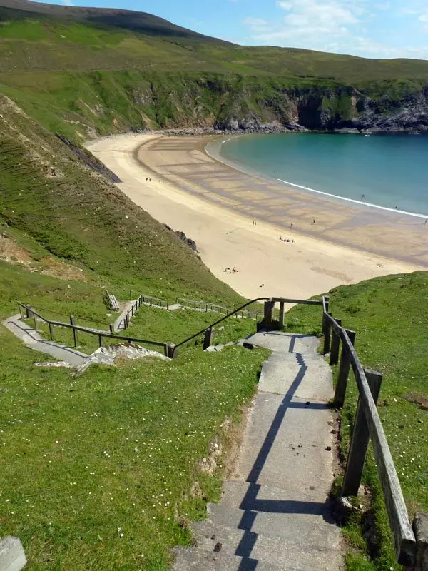 Steps leading to golden sandy beach with blue water.