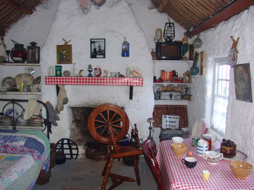 Traditional spinning wheel standing in front of fireplace with old ornaments.