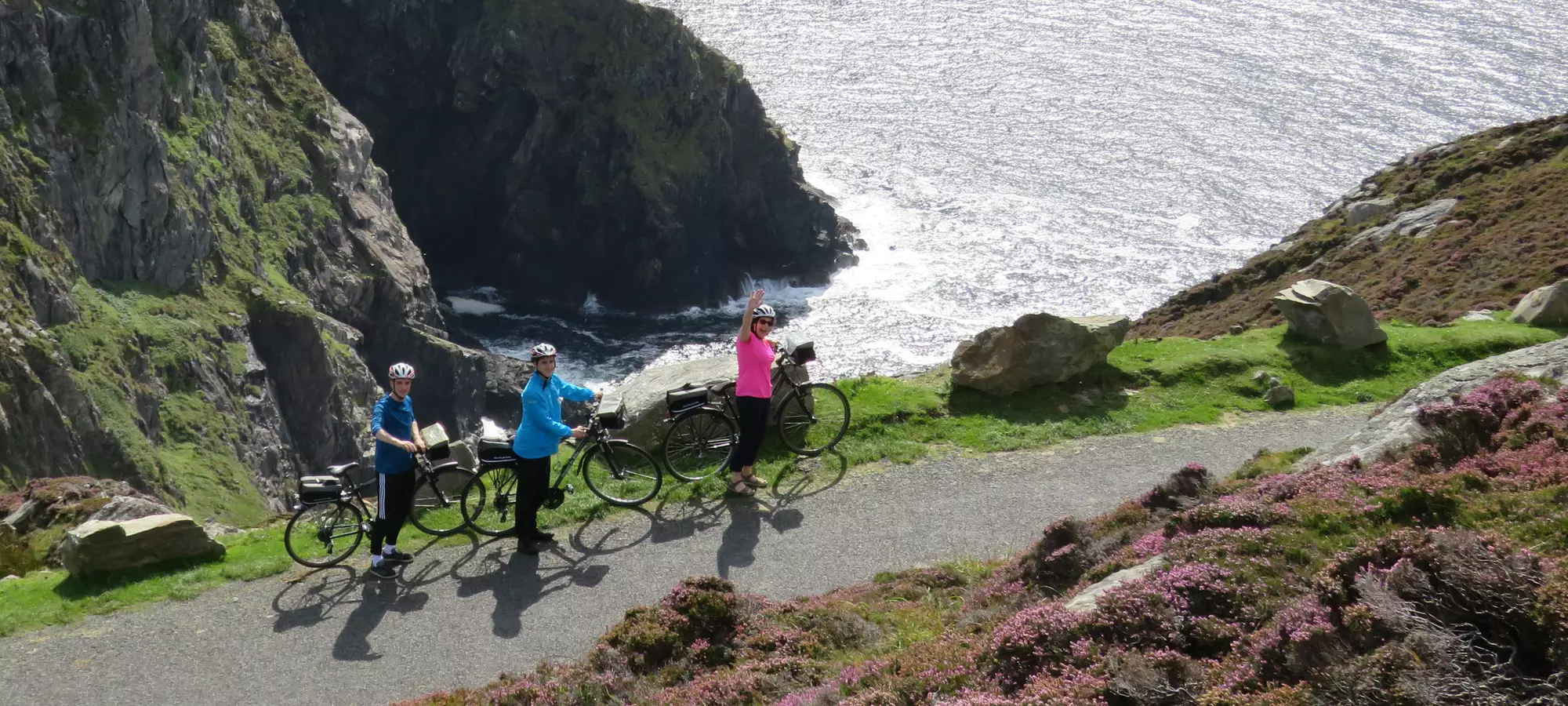 3 cyclists wearing bright colours along coast.