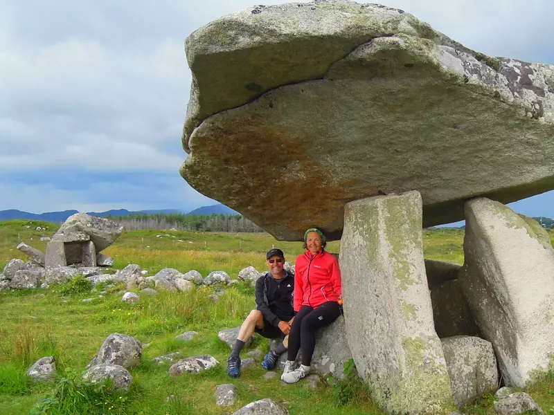 Two people sitting under the cap stone of a dolmen